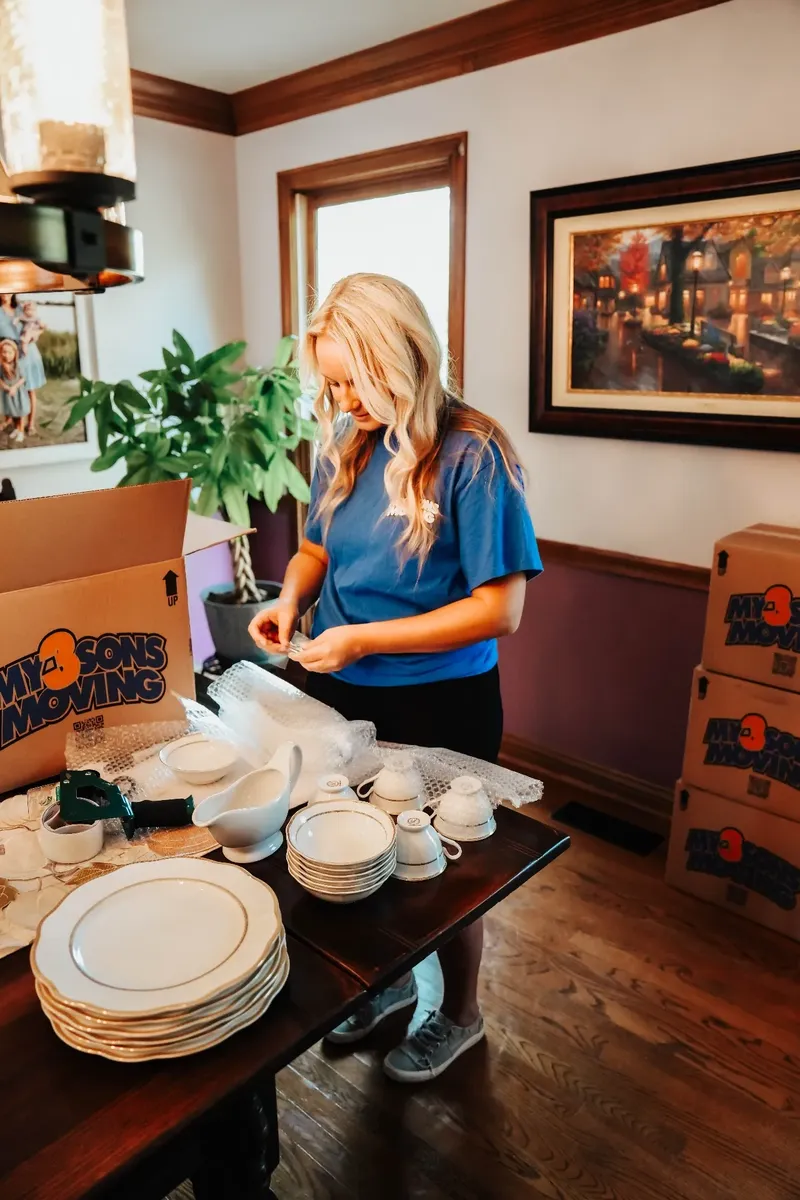 Professional packer carefully wrapping dishes and glassware